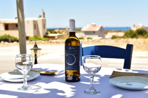 埃拉福尼西岛Rooms Kochilas Elafonisi的桌子上摆放着一瓶葡萄酒和眼镜