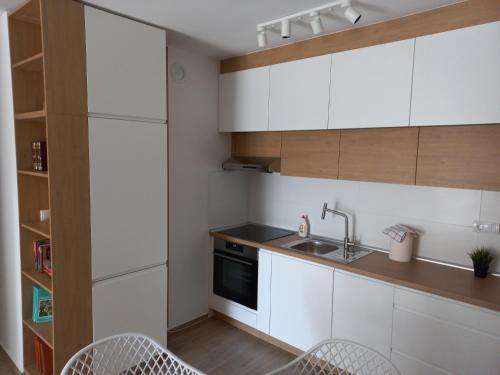 UbLovely one bedroom apartment的厨房配有白色橱柜、水槽和椅子