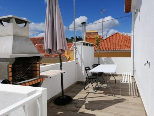 蒙塔吉尔Alojamento Justo - vila de Montargil的阳台配有雨伞和桌椅。