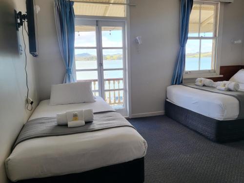 芒奥努伊Mangonui Hotel的酒店客房设有两张床和窗户。