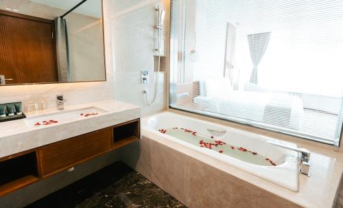 曼德勒Ease Hotel的带浴缸、水槽和窗户的浴室