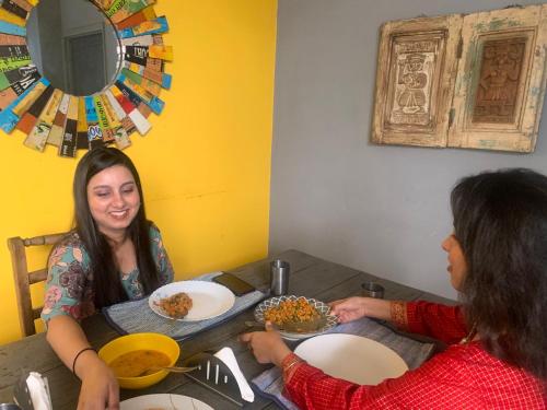 新德里Bed & Chai Guesthouse的两个坐在餐桌上吃食物的女人