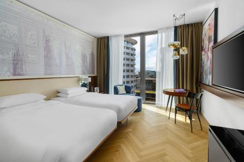 维也纳Andaz Vienna Am Belvedere - a concept by Hyatt的酒店客房设有两张床和一台平面电视。