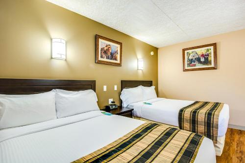 Peace RiverQuality Hotel & Conference Centre Sawridge的配有两张床的酒店客房中的两张床