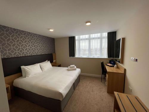 伦敦Best Western Northfields Ealing Hotel的配有一张床和一张书桌的酒店客房