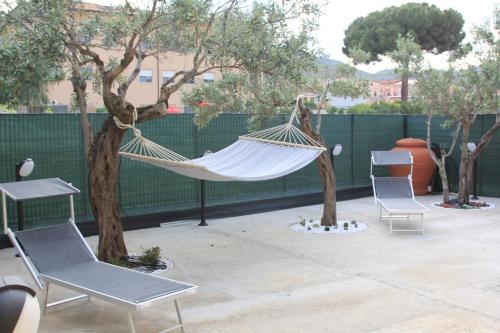 卡坦扎罗AGAS Exclusive Apartment的天井上的吊床,配有两把椅子和树木