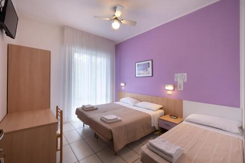 里米尼乔奥多酒店的酒店客房设有两张床和紫色的墙壁。