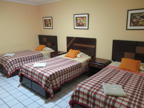 利马Kurmi Hostel Lima Airport的酒店客房 - 带两张带橙色枕头的床