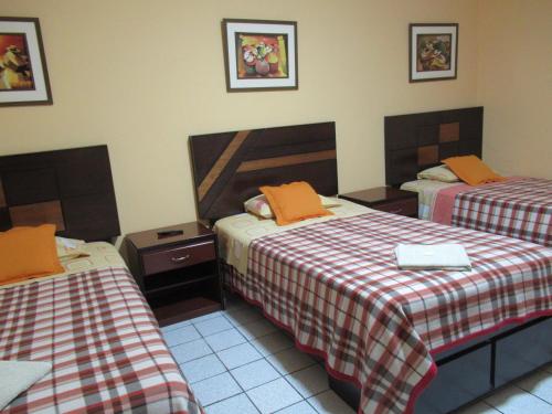 利马Kurmi Hostel Lima Airport的酒店客房 - 带两张带橙色枕头的床