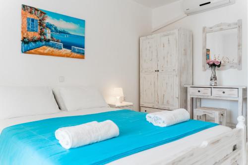 帕尔加Villa Kallithea的白色卧室配有蓝色的床和2条毛巾