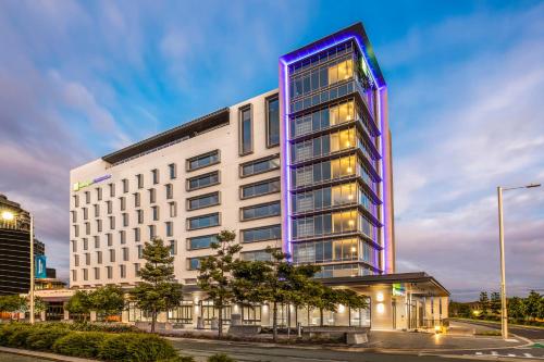 玛志洛Holiday Inn Express & Suites Sunshine Coast, an IHG Hotel的一座高大的白色建筑,上面有紫色的灯光