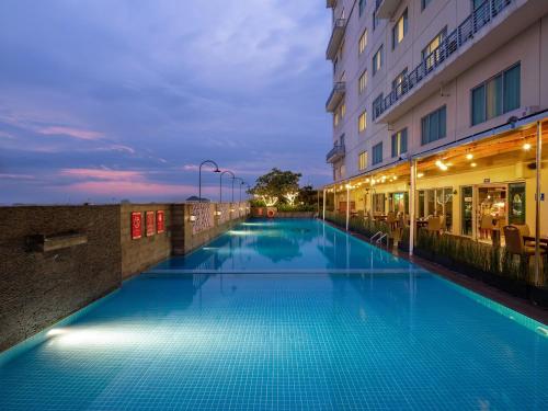 梭罗ASTON Solo Hotel的一座游泳池,在晚上在建筑物前