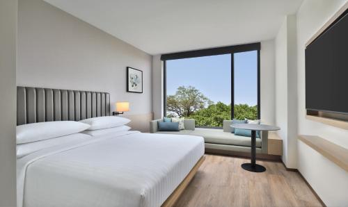 巴罗达Fairfield by Marriott Vadodara的白色的卧室设有一张大床和一个大窗户