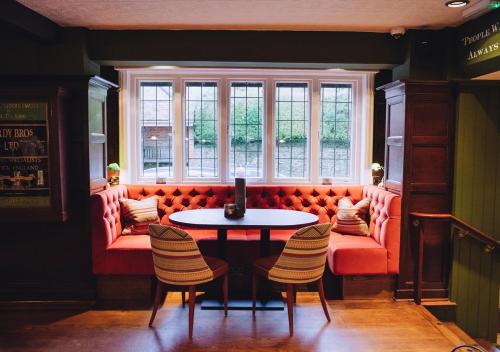吉尔福德德拉蒙德奥尔伯里宾馆的一间设有红色沙发、桌子和椅子的客房