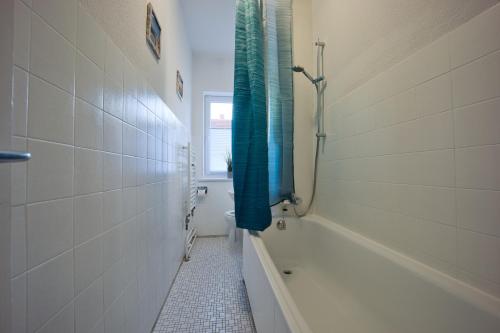 吕贝克HejU - Parking - Kitchen - Netflix - Kingsize Bett的浴室配有浴缸和淋浴,淋浴为蓝色的浴帘