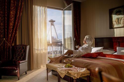 布拉迪斯拉发德文酒店的坐在酒店房间床上的女人
