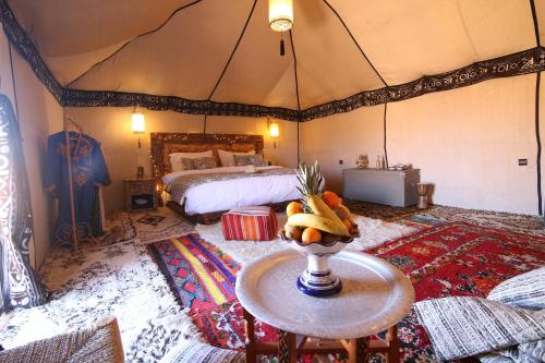 梅尔祖卡Luxury traditional Tent Camp的帐篷内带一张床和一张桌子的房间