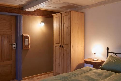 LeutersdorfDoppelzimmer Dora Oberlausitzer Hof的一间卧室配有一张床和一个木制橱柜