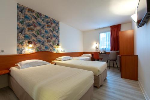 勒布伊Deltour Hotel Le Puy En Velay的酒店客房设有两张床和一张桌子。