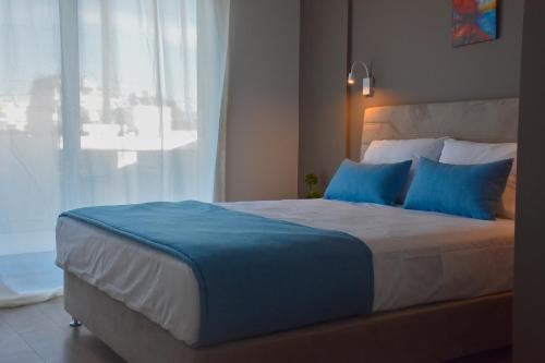 雅典Thisean Modern Suites By Athens Stay的一间卧室配有一张带蓝色枕头的床和一扇窗户。
