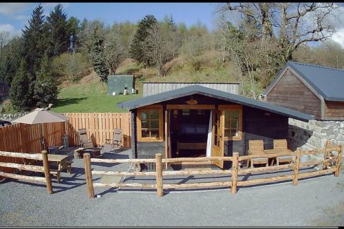 牛顿斯图尔特Luxury Cabin in the Magical Galloway Forest Park的小木屋前方设有木栅栏