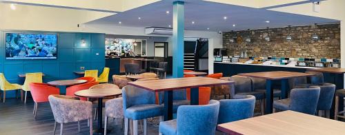 阿蒙兹伯里Almondsbury Inn & Lounge的一间带桌椅的餐厅和一间酒吧