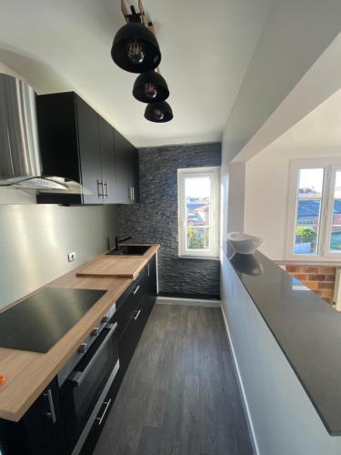 布尔日Superbe appartement proche CV的厨房配有黑白橱柜和木地板