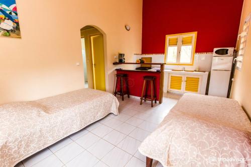 Saint-Louis奥村德梅纳德公寓的带两张床的房间和带红色墙壁的厨房
