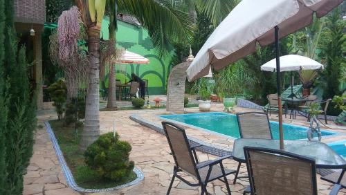 圣安东尼奥-杜皮尼亚尔Pousada Família的一个带椅子和桌子的游泳池以及一把遮阳伞