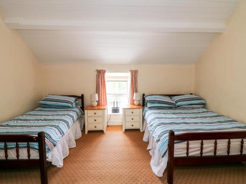 海上费萨德Grange Farmhouse的带窗户的客房内设有两张单人床。