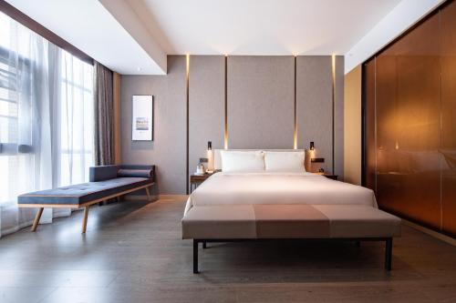 昆明昆明滇池西山区政府亚朵酒店的一间卧室配有一张床、一张长凳和一个窗户。