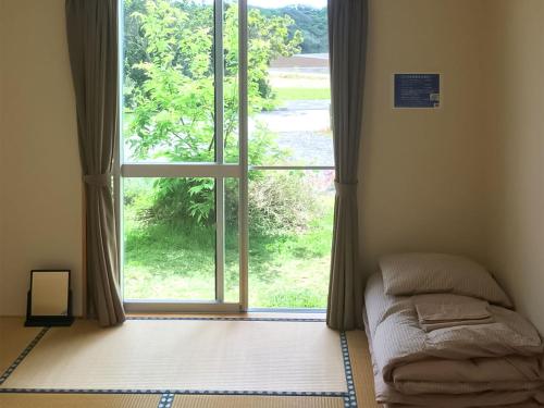 宫古岛奴松那卡旅馆的卧室在窗户前配有一张床