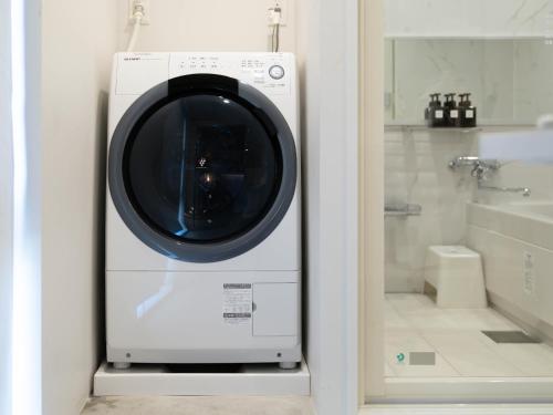 东京艺术家酒店 - 秋叶原BnA一室公寓的带浴缸的浴室内的洗衣机