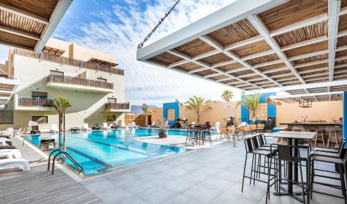 埃拉特Almogim Suites Eilat的户外庭院设有游泳池和桌椅。