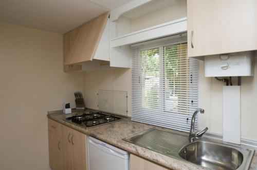 埃尔罗西奥阿尔迪露营酒店的厨房配有白色橱柜、水槽和窗户。