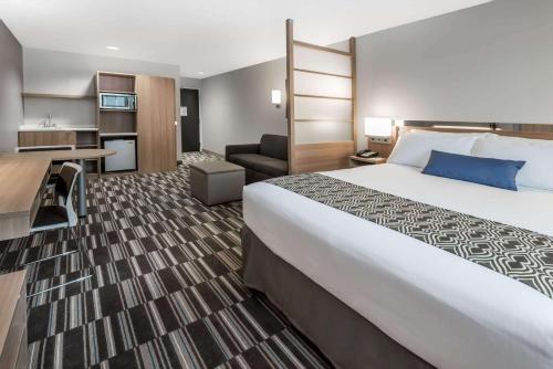 彭延彭延温德姆麦克罗特客栈&套房的酒店客房设有一张大床和一张书桌。