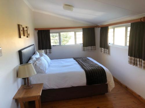 温特顿Bee’s Knees Cottage的一间卧室设有一张床和两个窗户。