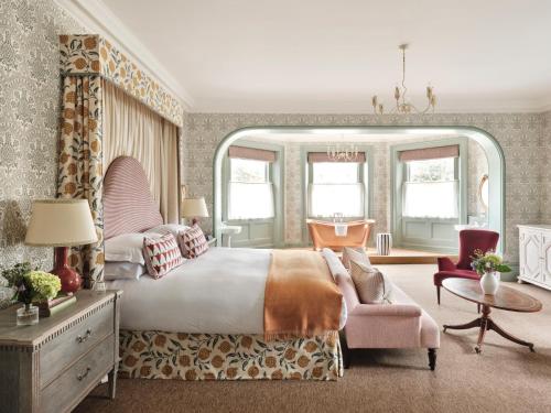 纽伯里The Retreat, Elcot Park的一间卧室配有一张大床和一张粉红色的椅子
