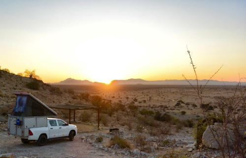 索利泰尔Camp Gecko - PRIVATE NATURE RESERVE; TENTED CAMP AND CAMPSITE的落日时停在沙漠中的一辆白色卡车