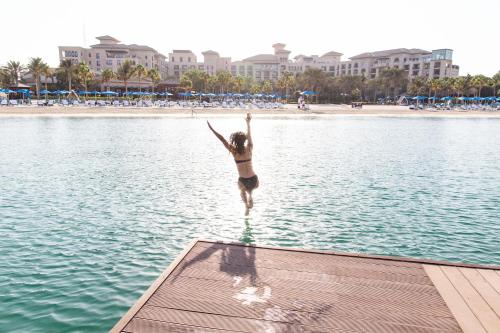 迪拜朱美拉海滩迪拜四季酒店的一位在海滩上跳水的女人