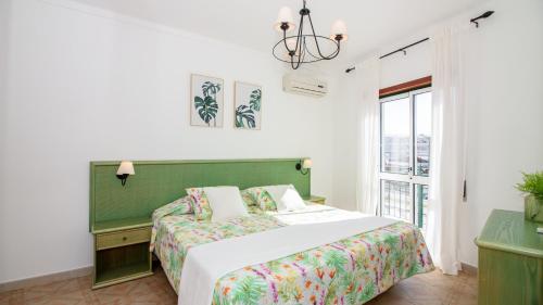 阿尔图拉Altura Vacations T2, Algarve的一间卧室配有一张带绿色床头板的床和窗户