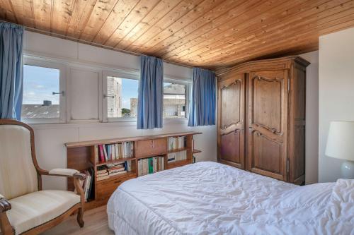 阿尔宗VUE MER Vacances en famille a cinq a Arzon的一间卧室配有一张床、一把椅子和窗户。