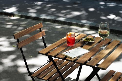 巴黎Hôtel Léopold - Orso Hotels的一张木桌,上面放着一杯葡萄酒和一本书