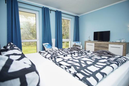 洛布F-1010 Strandhaus Mönchgut Bed&Breakfast DZ 25 Garten, strandnah, inkl Frühstück的一间卧室配有一张蓝色墙壁和窗户的床