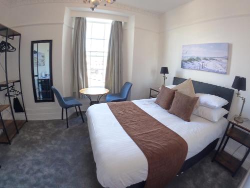 法尔茅斯The Grove Falmouth的酒店客房带一张床、一张桌子和椅子