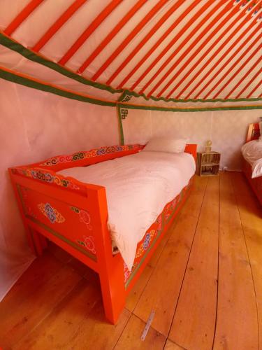 MonieuxA Ventoux Yourte的铺有木地板的客房内的橙色床