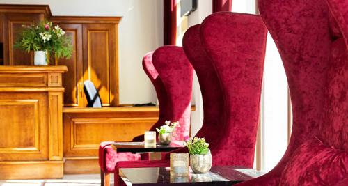 莱比锡莱比锡城维克特雷斯登斯酒店的一间设有红色椅子和鲜花桌的房间