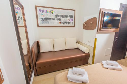 米兰Hotel Repubblica的一间设有棕色皮沙发和镜子的等候室