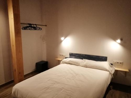 LarrauriCasa rural Lastoetxe的卧室配有白色的床和墙上的2盏灯。