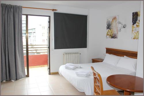 马略卡岛帕尔马戈米拉公园公寓式酒店的一间卧室配有一张床、一张桌子和一个窗户。
